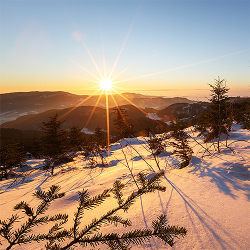 Winterlandschaft unter einem wolkenfreien, blauem Himmel und strahlender Sonne.