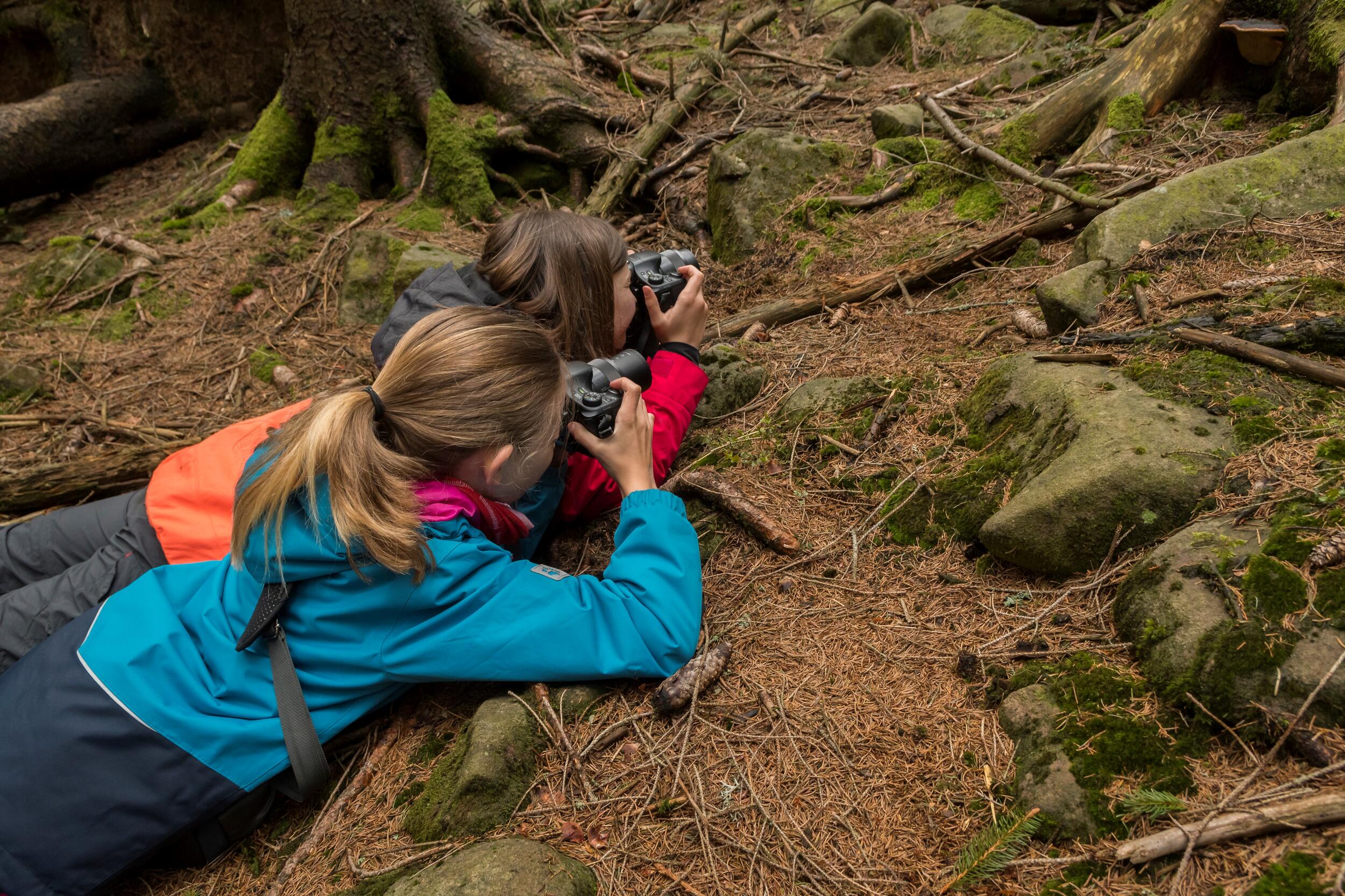 zwei Mädchen machen auf dem Bauch liegend Fotos © Nationalpark Schwarzwald
