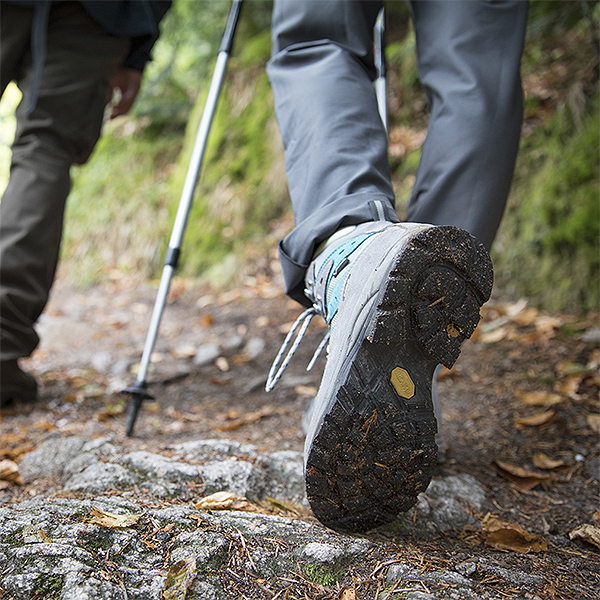 Aufnahme von den Wanderschuhen einer Person. Die Person macht gerade einen Schritt, die Sohle des Schuhs zegt in die Kamera