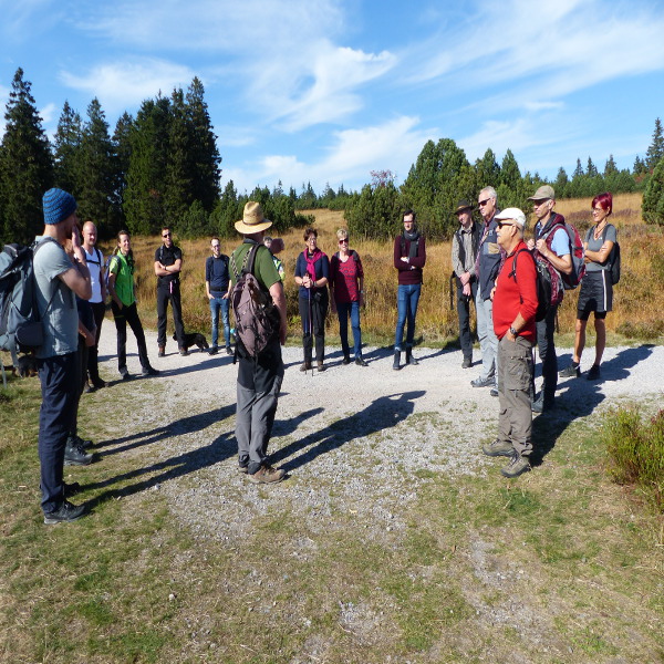 Nationalparkpartner stehen bei einer Führung im Gebiet des Nationalparks beisammen und hören dem Ranger zu.