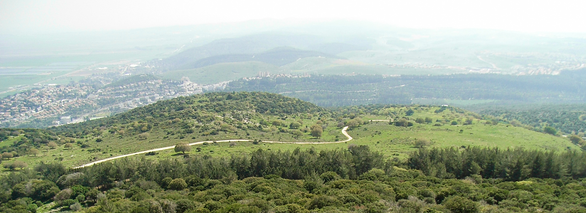 Blick auf eine halboffene Landschaft auf einer Bergkuppe.  Ein Weg führt über die Fläche. Im Hintergrund sieht man ähnliche Hügel.
