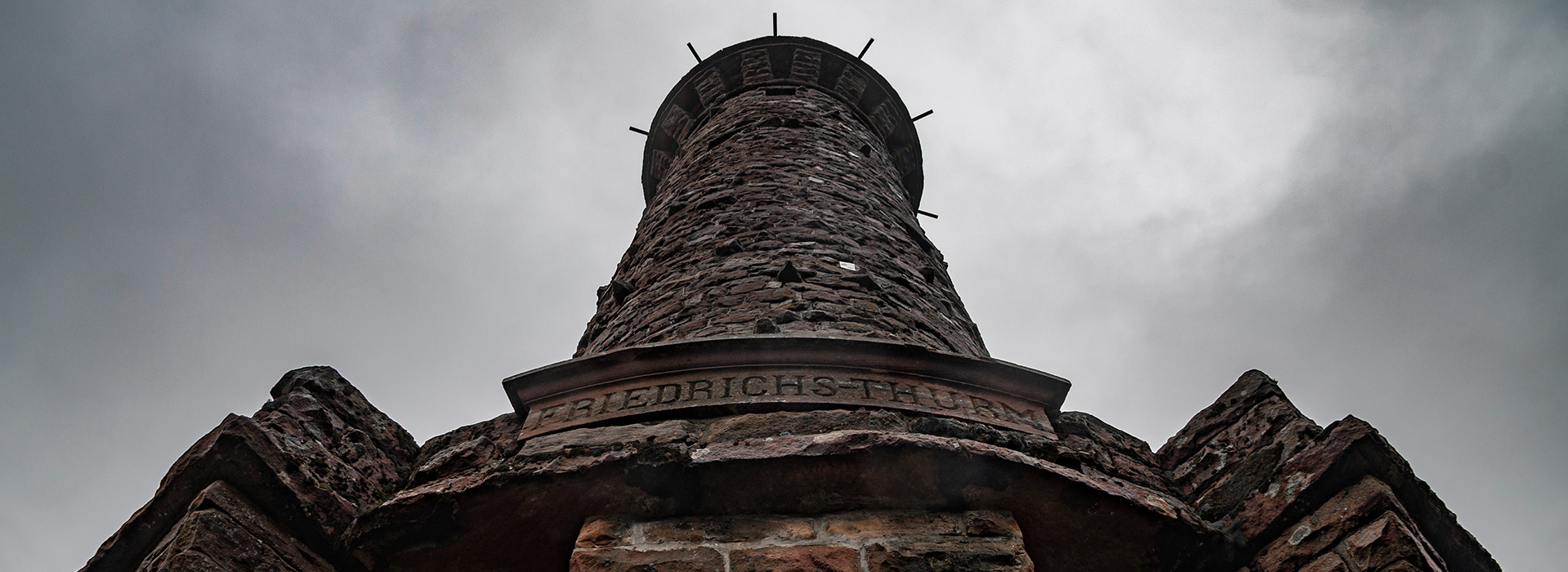 Blick vom Fuß des Friedrichsturm an der Badener Höhe zum Himmel. Der Turm besteht aus Steinen, die Inschrift über dem Eingang lautet "Friedrichs-Thurm".