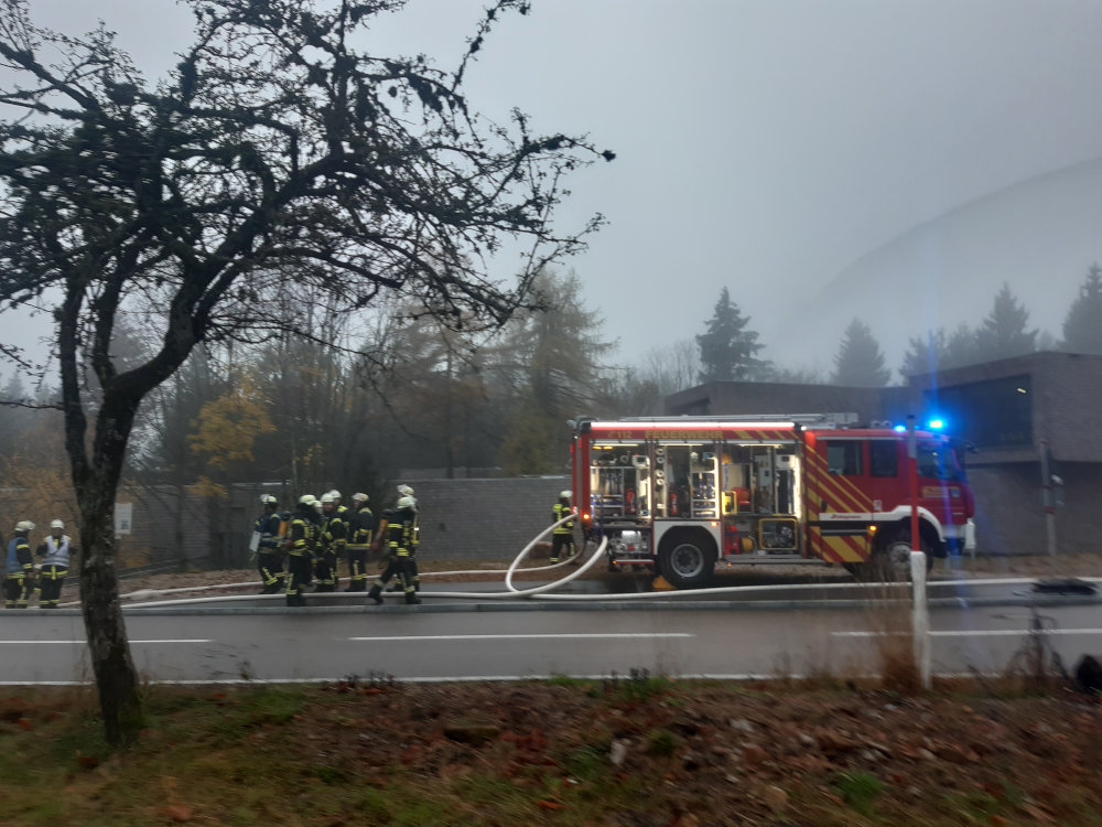 Feuerwehrfahrzeug mit eingeschalteten Blau- und Warnlichtern und geöffneter Materialklappe. 