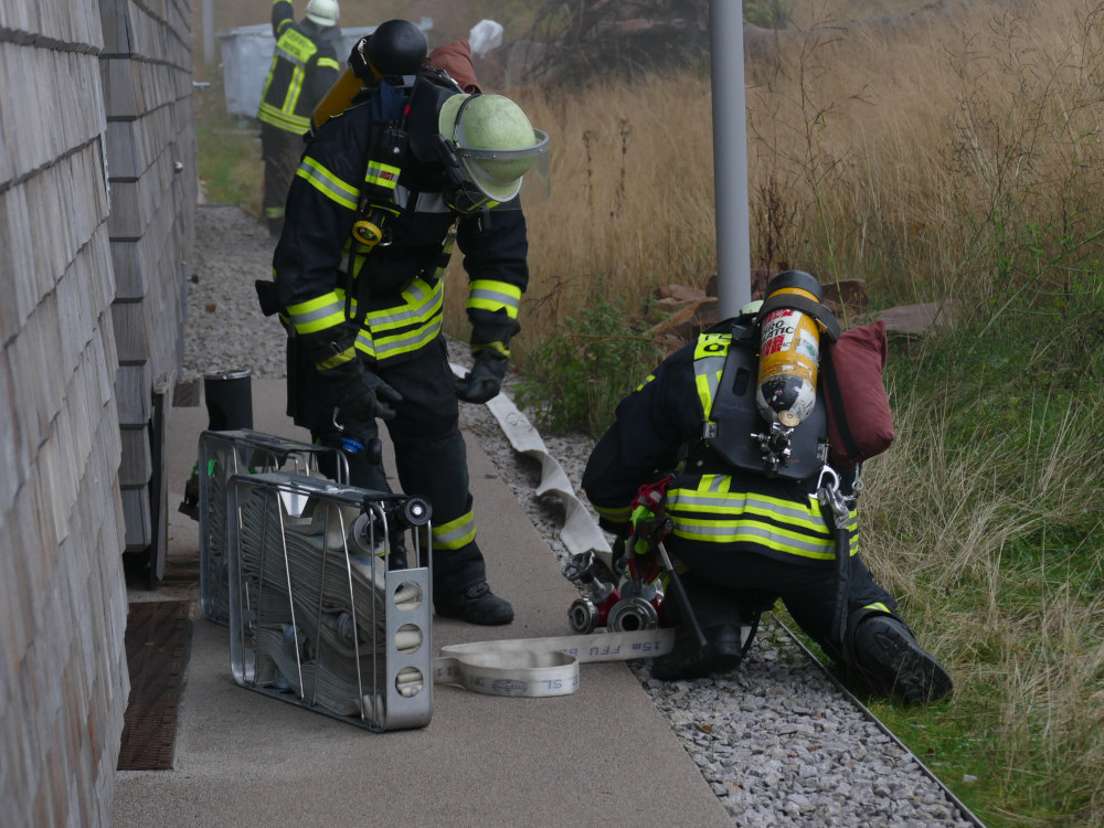 Zwei Feuerwehrleute bereiten einen Wasserschlauch vor.