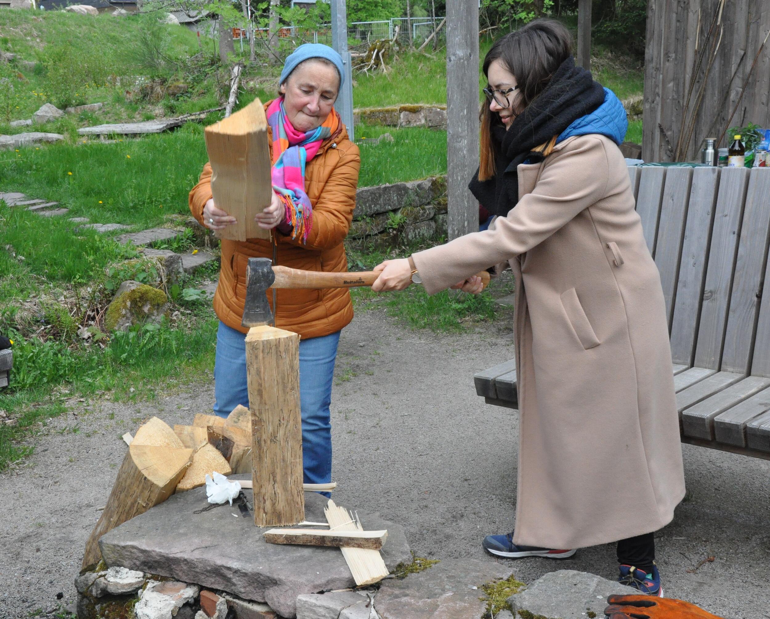 Zwei Frauen hacken mit einer Axt Holz