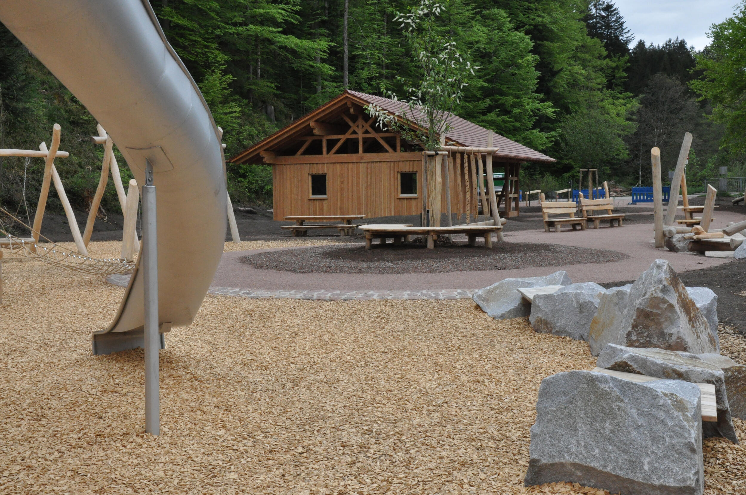 Eine Hütte aus Holz, vor der Hütte ist ein Spielplatz. 