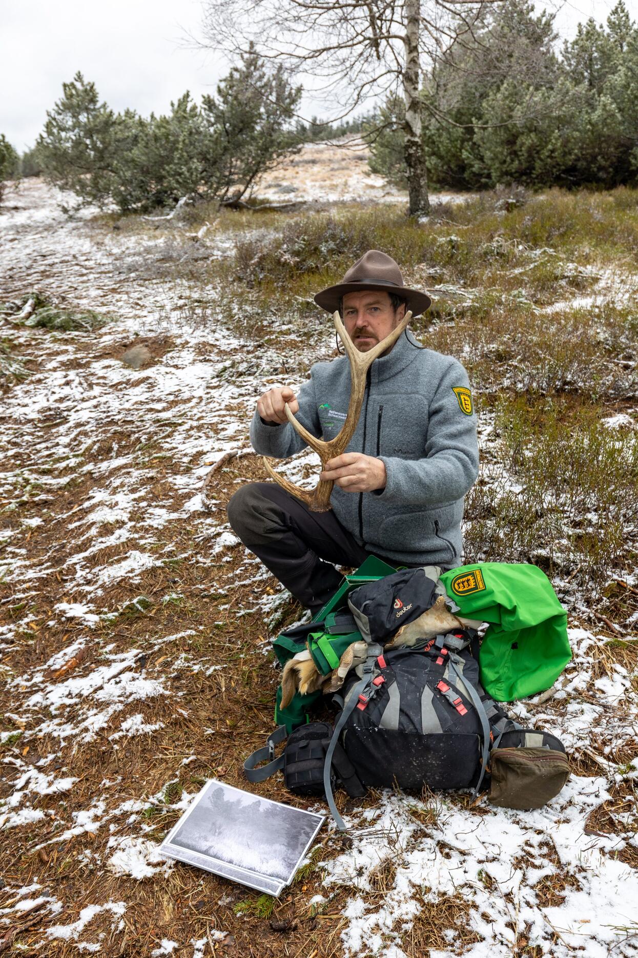 Ranger Jens kniet am Boden, vor ihm sein Rucksack, in der Hand ein Geweih