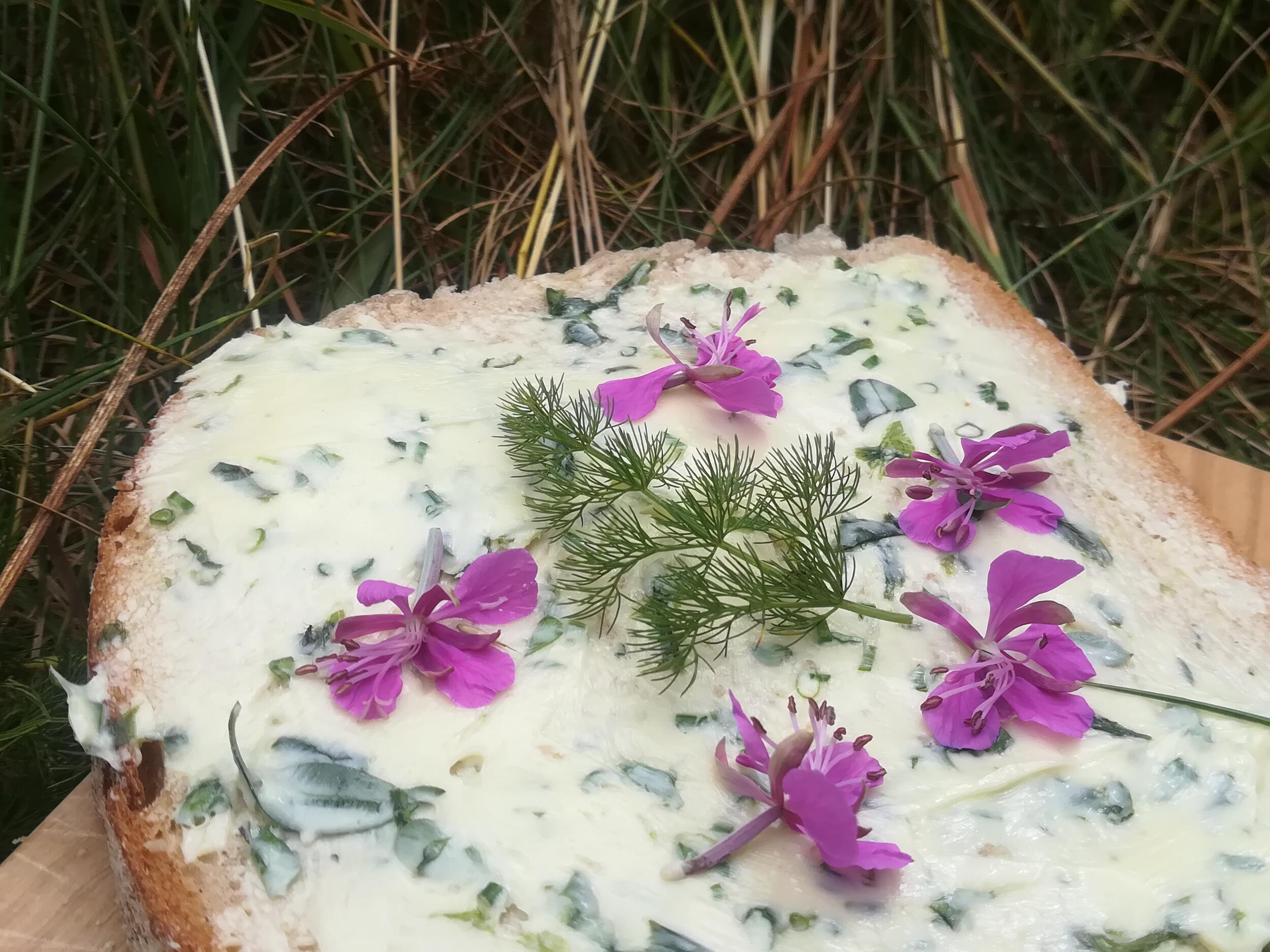 Brot mit weißem Aufstrich und lila Blüten darauf