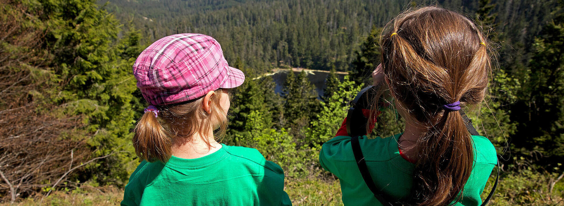 Zwei Mädchen schauen mit Ferngläsern auf einen Waldsee. Foto: Ulrike Klumpp