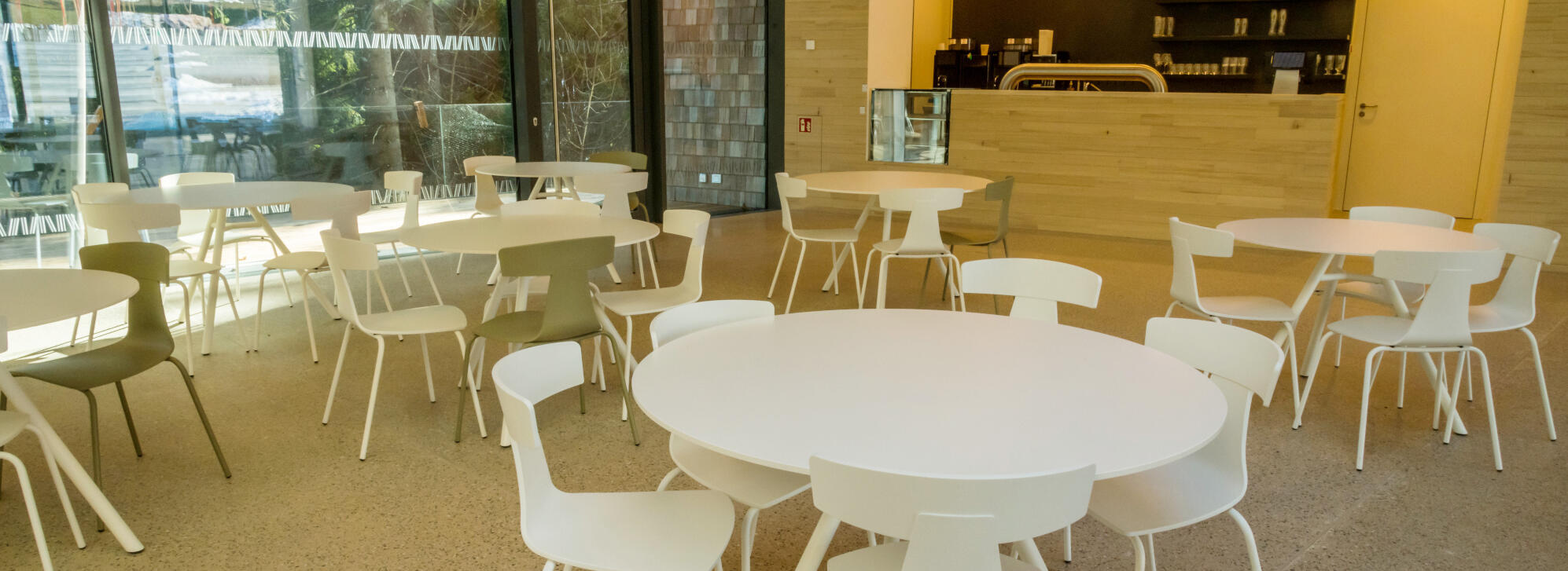 Ein Café mit mehreren weißen Stühlen und Tischen. Hinten ist ein Tresen. Foto: Luis Scheuermann