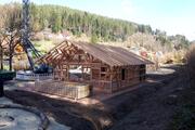 Das Fachwerk der Hütte steht bereits. Davor liegen die Dachbauteile.