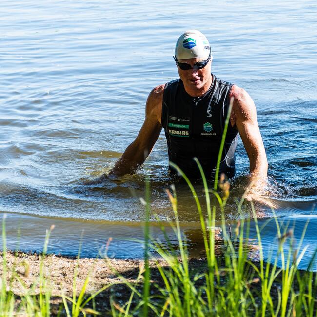 Ein Mann in Schwimmkleidung steigt aus dem Wasser.