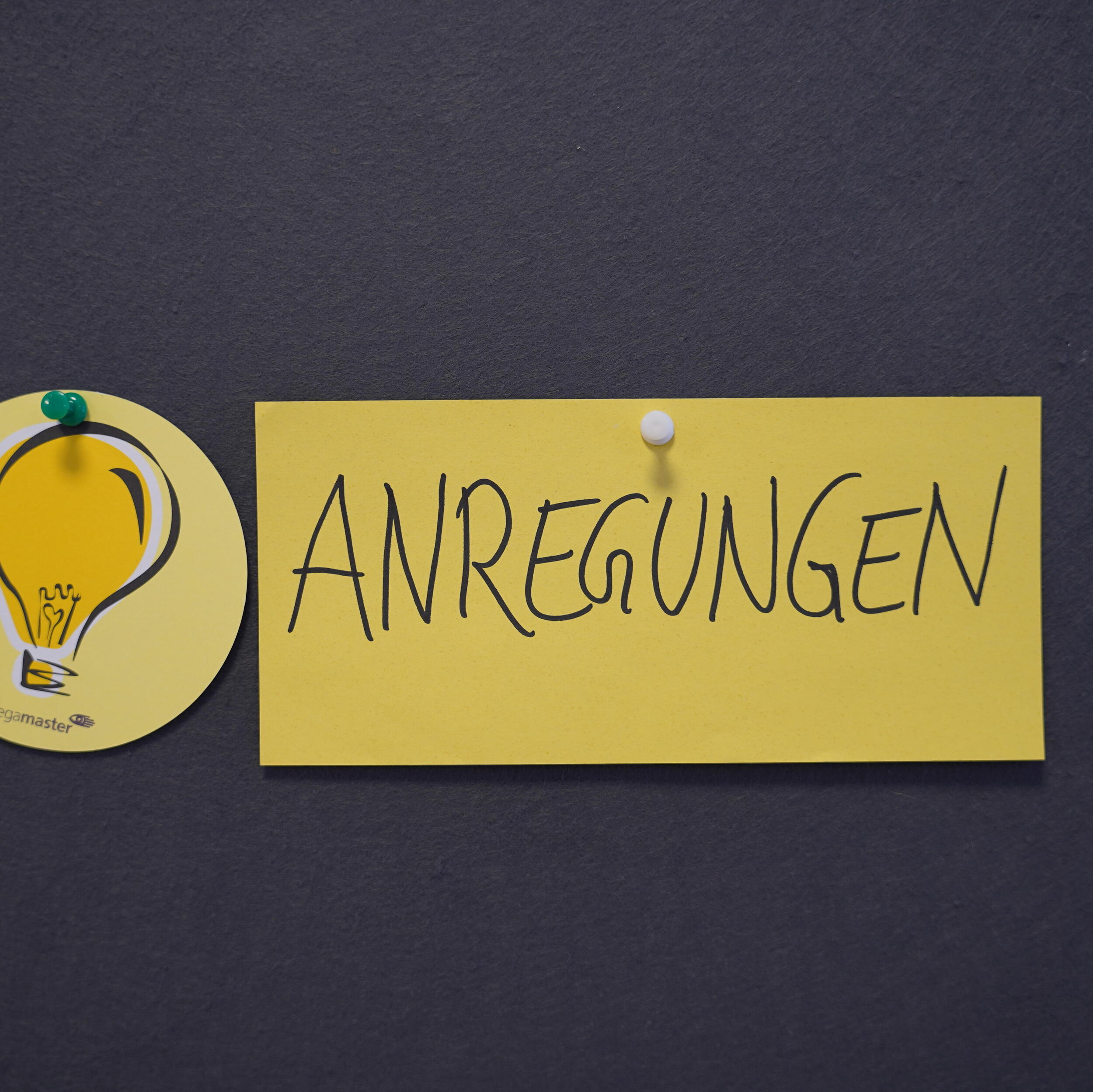Pinwand mit gelbem Post it auf dem "Anregungen" geschrieben steht