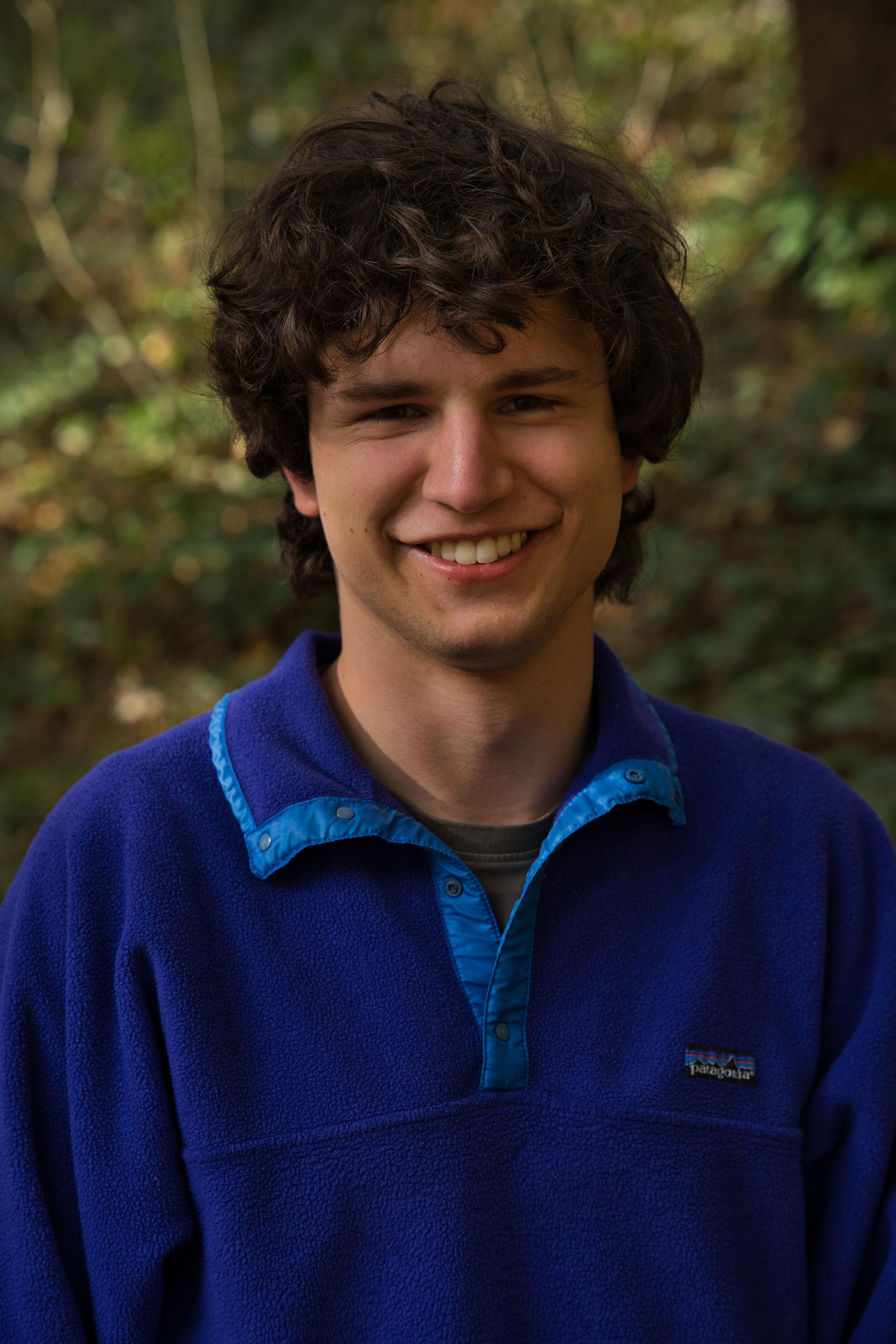 Ein junger Mann in einem blauen Pullover schaut in die Kamera. Foto: Clara Kiefer