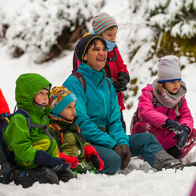 Kinder und Erwachsene sitzen im Schnee © Luis Scheuermann (Nationalpark Schwarzwald)