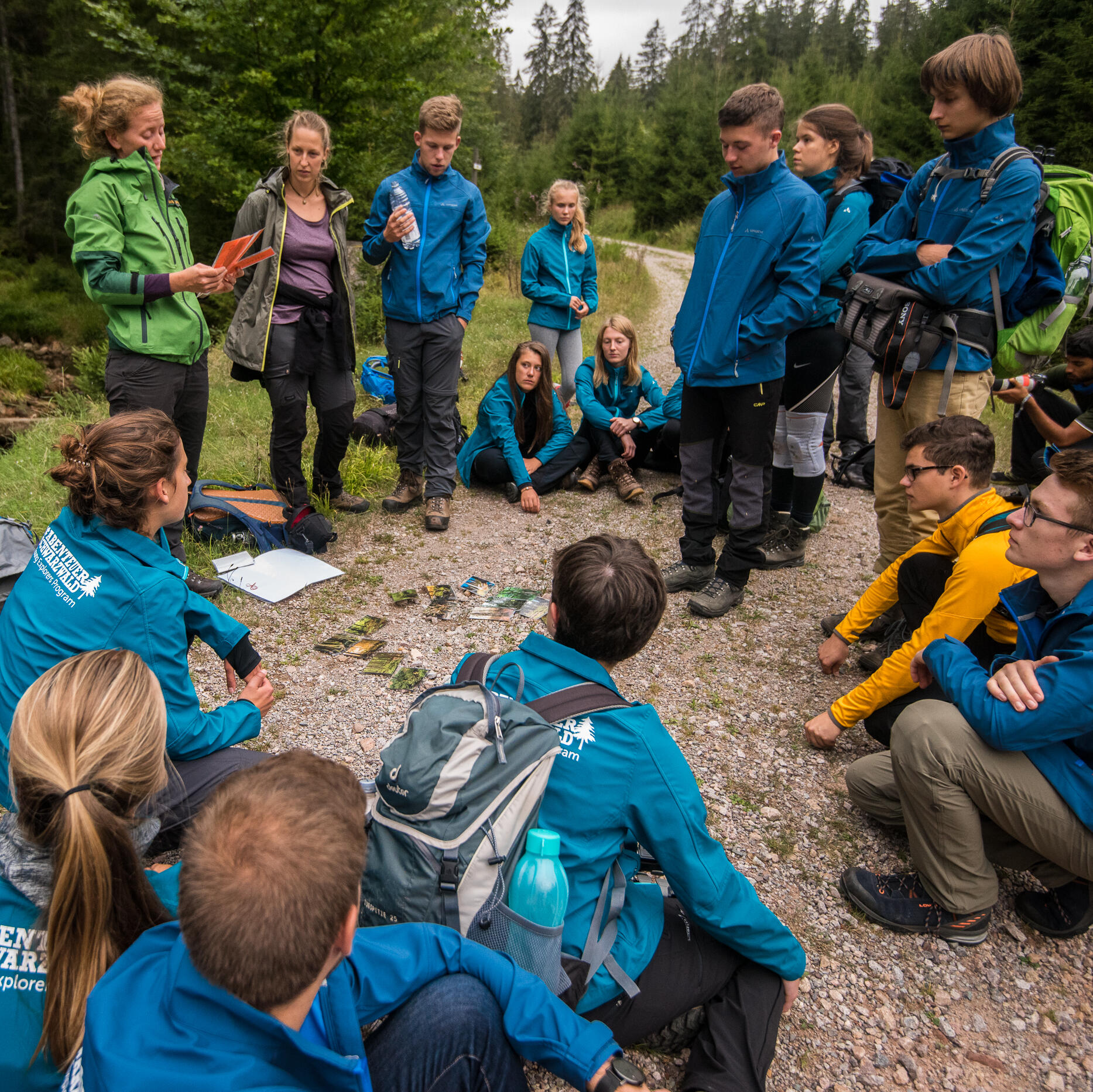 Young Explorers stehen und sitzen im Kreis um eine Nationalparkmitarbeiterin  © Dimitry Sharomov (Nationalpark Schwarzwald)
