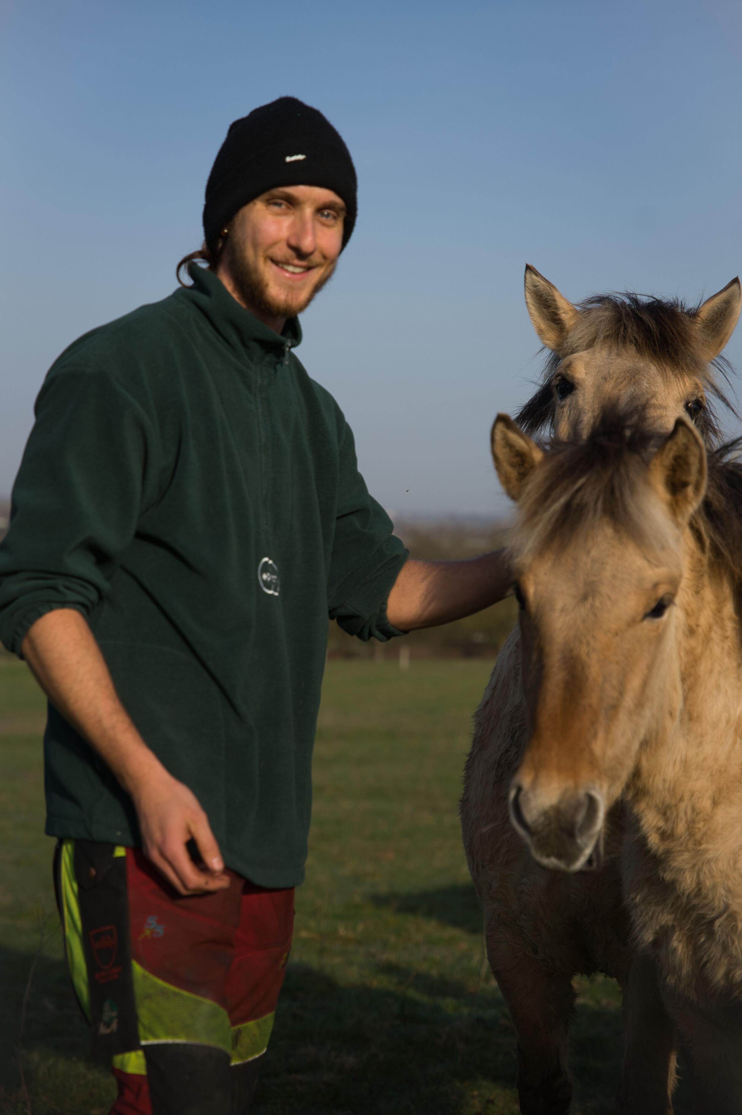 Ein junger Mann mit einer schwarzen Mütze steht neben einem Pferd. Foto: Jonas Humm 