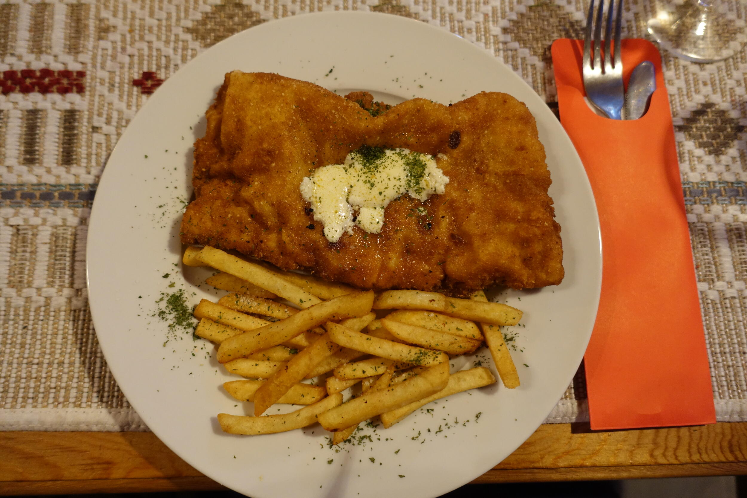 Ein Telle mit einem panierten Stück Fleisch und Pommes