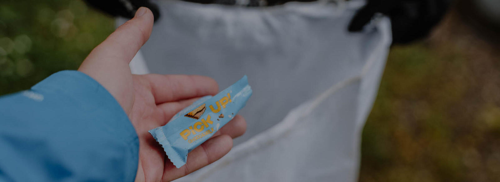 Eine Plastikverpackung wird im Wald aufgehoben