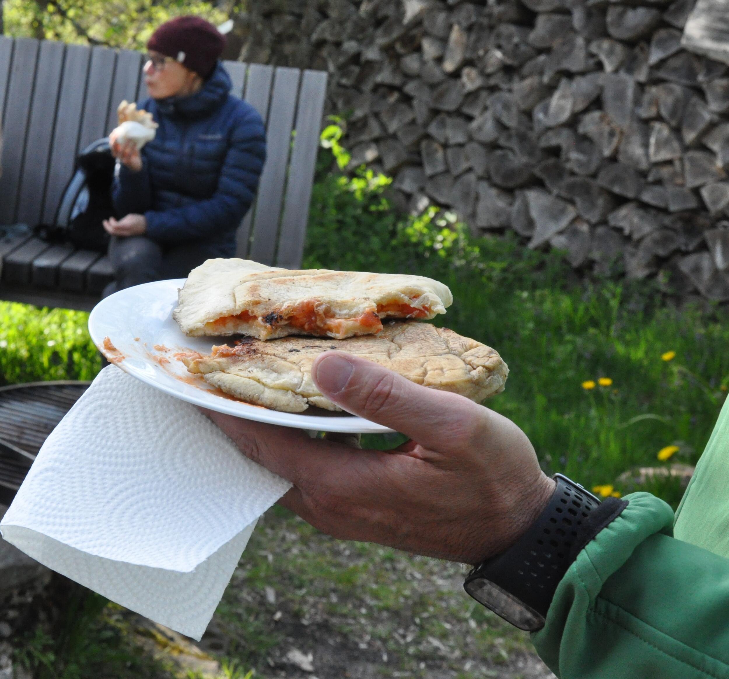 Ein Hand mit Teller, darauf zwei Stücke fertige Calzone