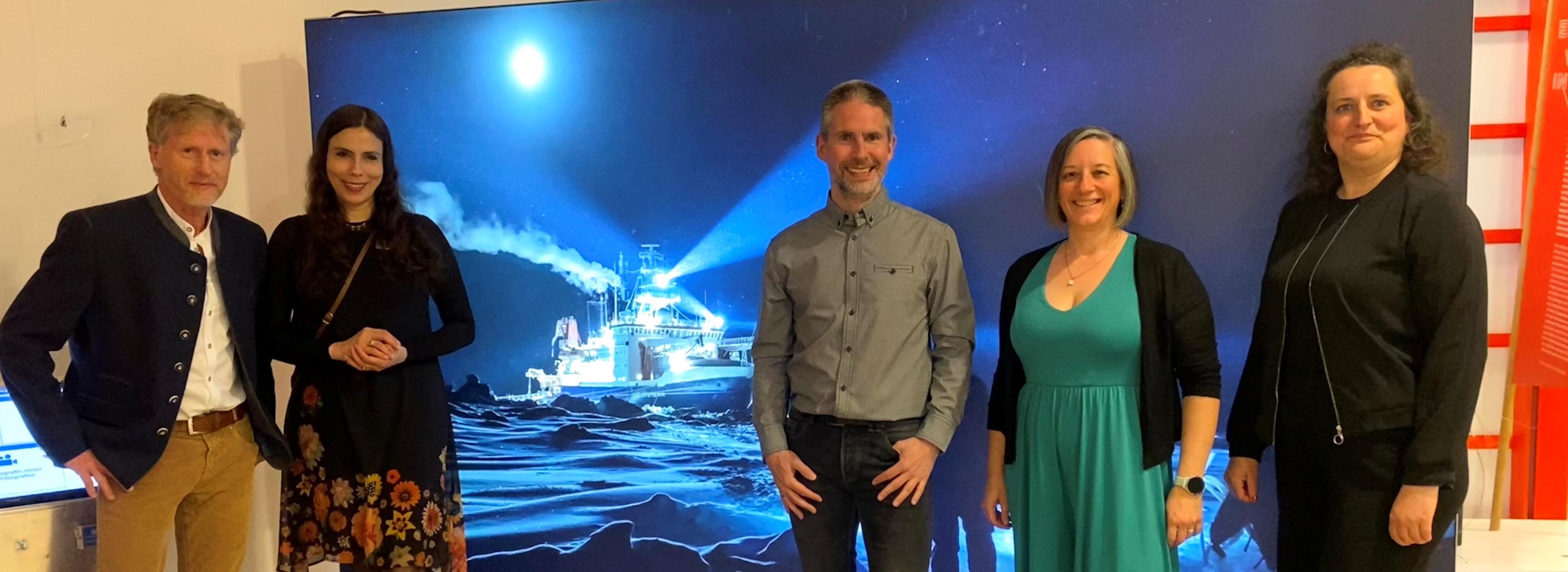 Auf dem Bild sind fünf Menschen vor einem großen Bild eines Schiffes zu sehen. Auf der linken Seite stehen Charly Ebel und Maite Graus vom Nationalpark Schwarzwald, auf der rechten Seite Dr. Marcel Nicolaus, Julia Nicolaus und Ruth Sommer vom Alfred-Wegener-Institut. 