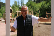 Ein Mann in blauer Weste und weißem Tshirt schaut durch einen weißen Holzrahmen, dahinter liegt ein Spielplatz. Foto: Anne Kobarg
