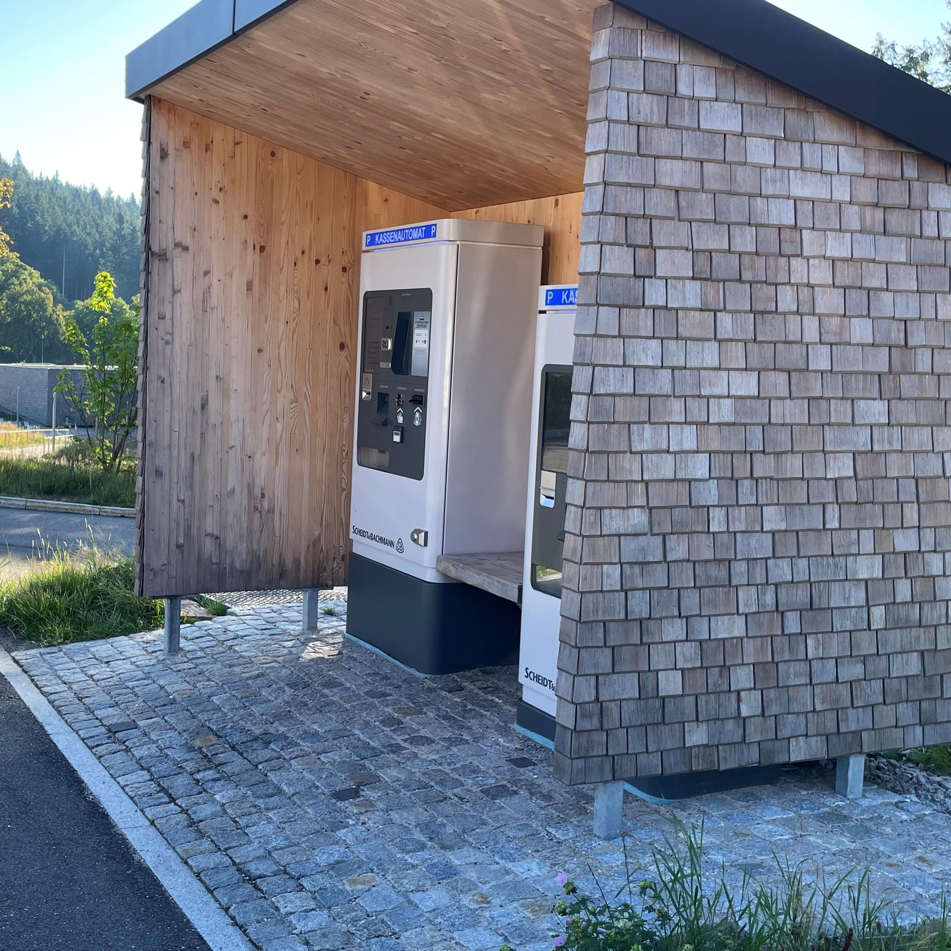 Seitliche Ansicht Unterstand Bezahlautomaten, zeigt Anstieg der Kopfsteinpflasterfläche vor Automaten.