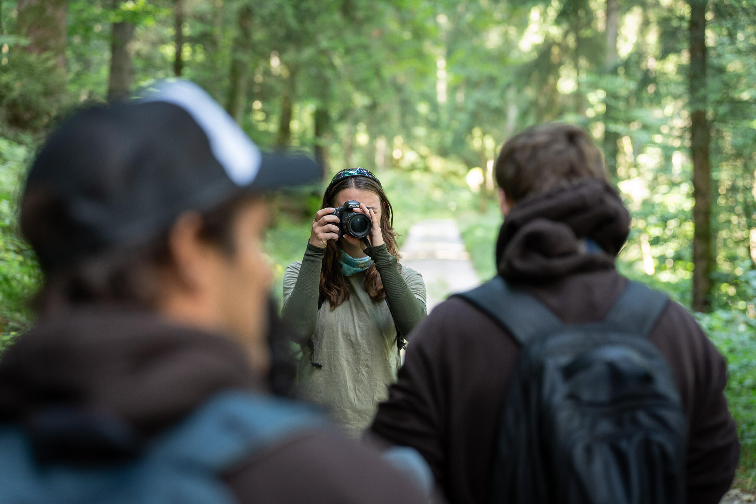 Eine junge Frau fotografiert zwei junge Männer im Wald. Foto: Vanessa Peter