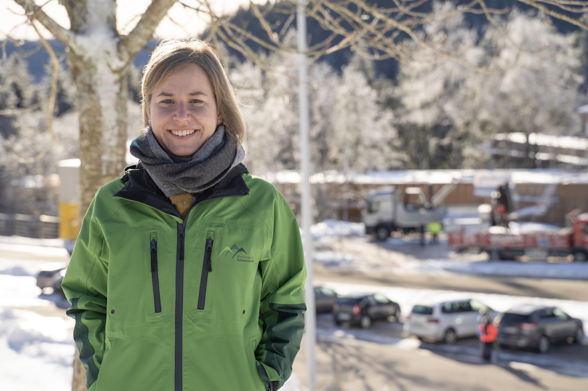 Eine Frau in grüner Jacke steht vor einem Parkplatz. Es ist Winter. Foto: Daniel Müller