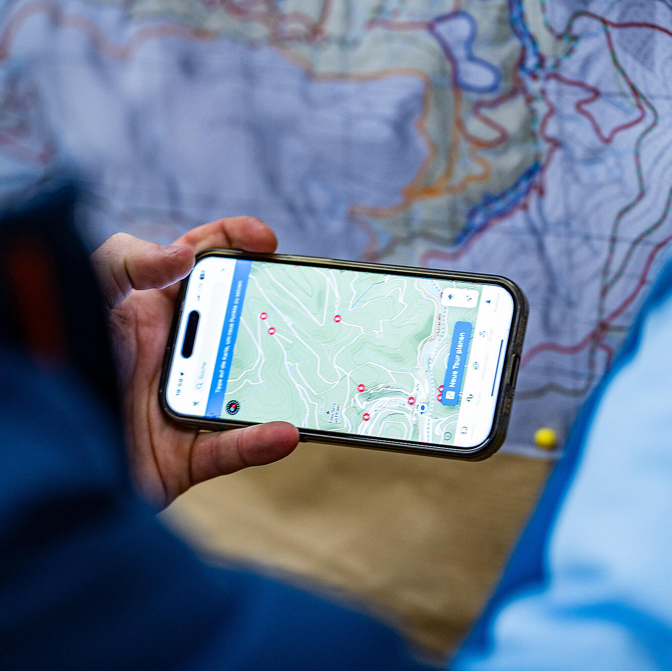 Mann gleicht Nationalparkkarte mit digitaler Karte auf seinem Handy ab.
