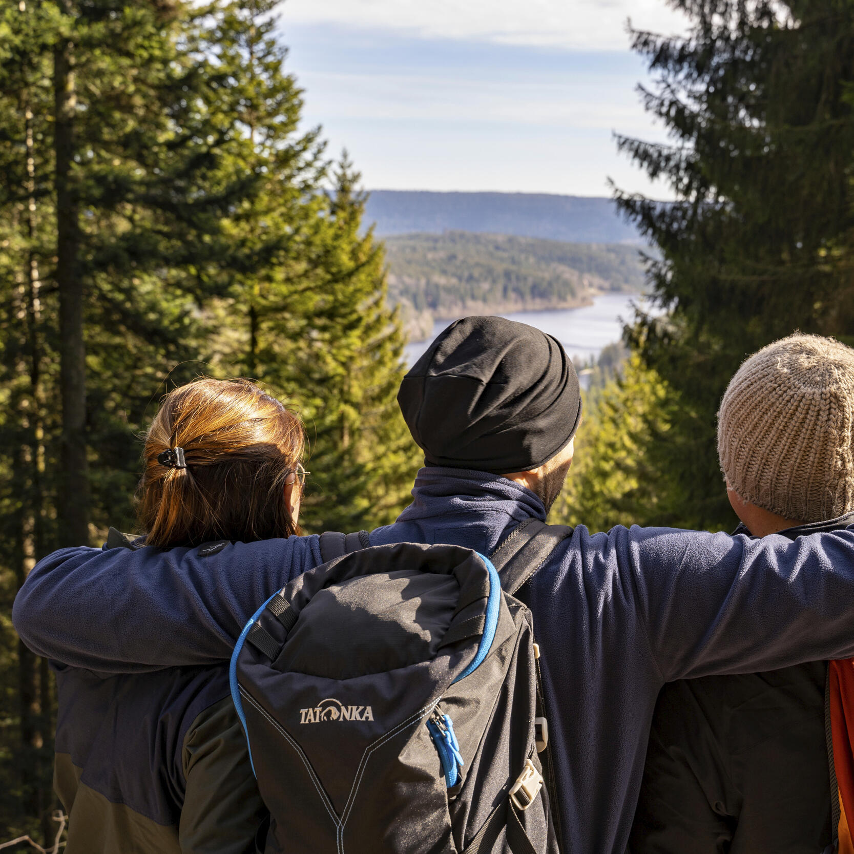drei Personen mit Wanderausrüstung schauen auf die Schwarzenbachtalsperre