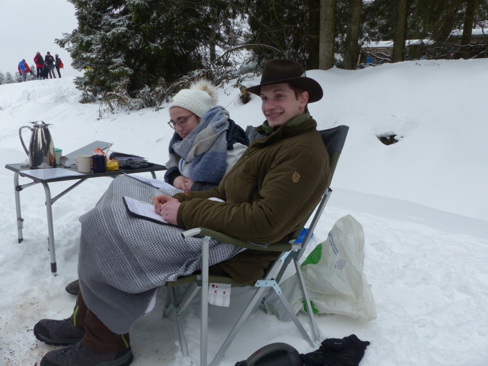 Abbildung 2: Zählende Personen bei der Winterzählung. Man sieht zwei sitzende Personen in einer Winterlandschaft.