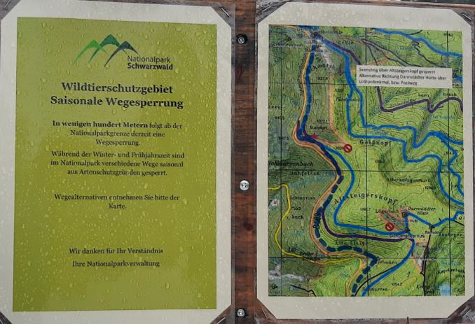 Abb.2: Zwei Hinweisschilder mit Erklärungstext zu einer Sperrung des Wildtierschutzgebiets und einen Karte mit alternativen Wanderwegen.zwei