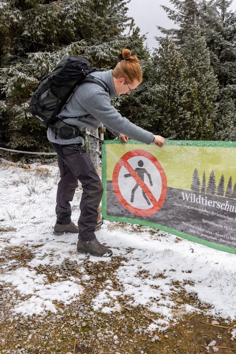 FÖJler Max bringt ein Banner mit einem "Betreten verboten"-Zeichen darauf an.