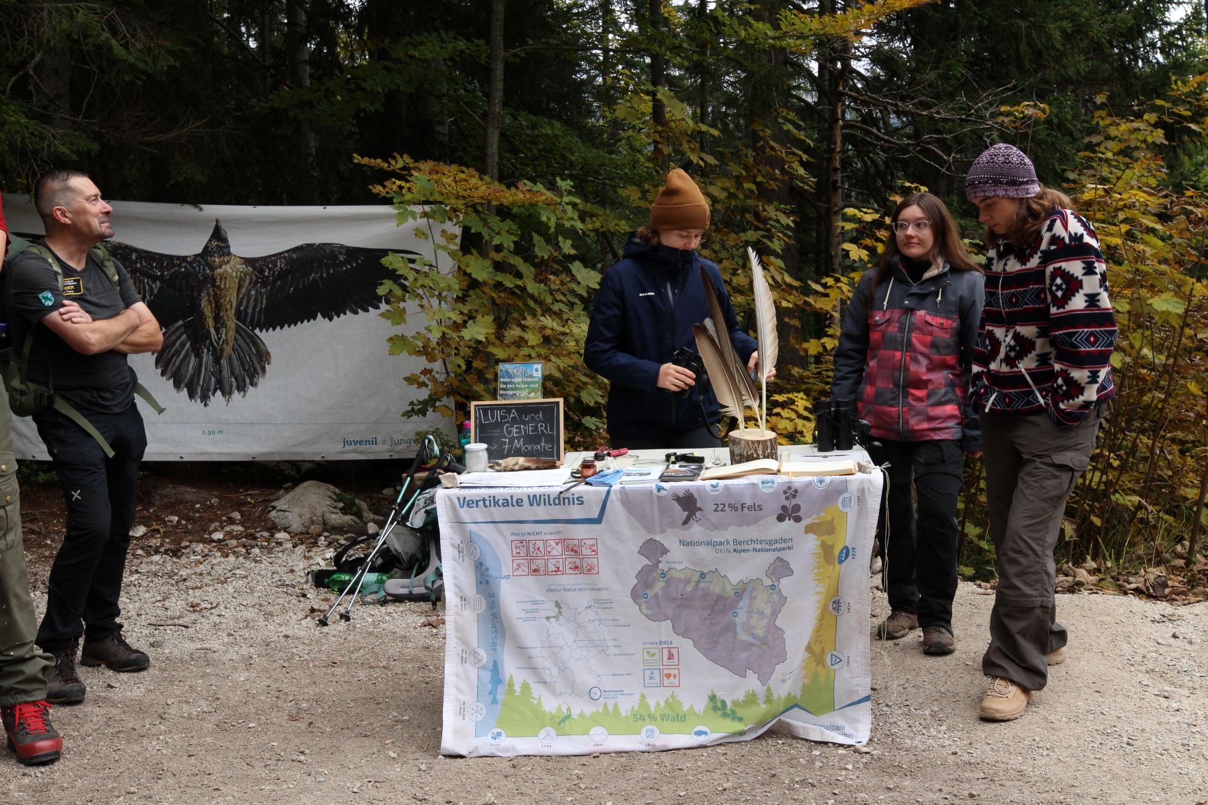 Man sieht eine Flagge mit der Karte und Landschaft vom Nationalpark Berchtesgaden. Drei Frauen geben Einblicke in die Karte. Foto: Nadine Berger 
