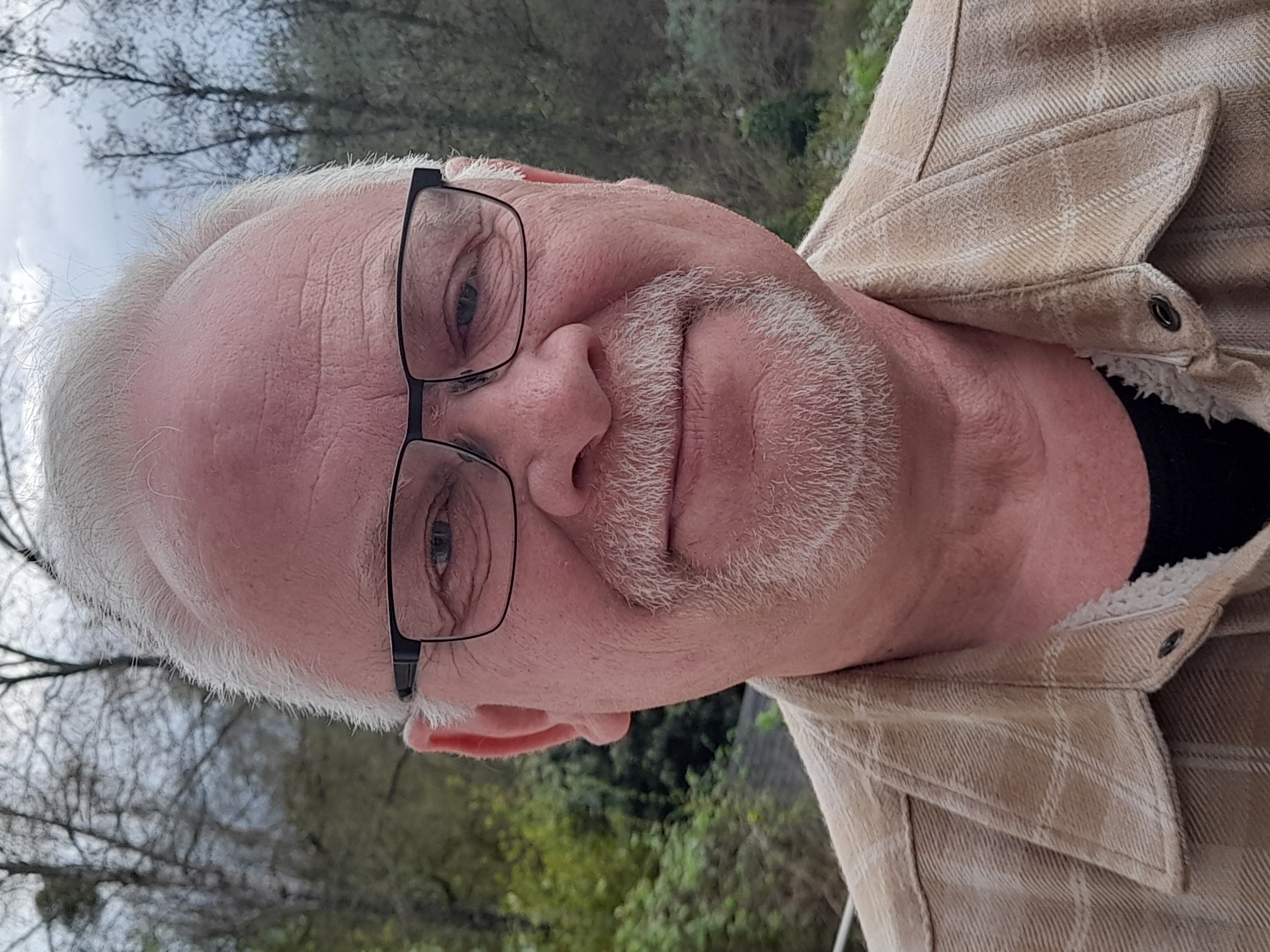 Ein Mann mit einer schwarzen Brille lächelt in die Kamera. 