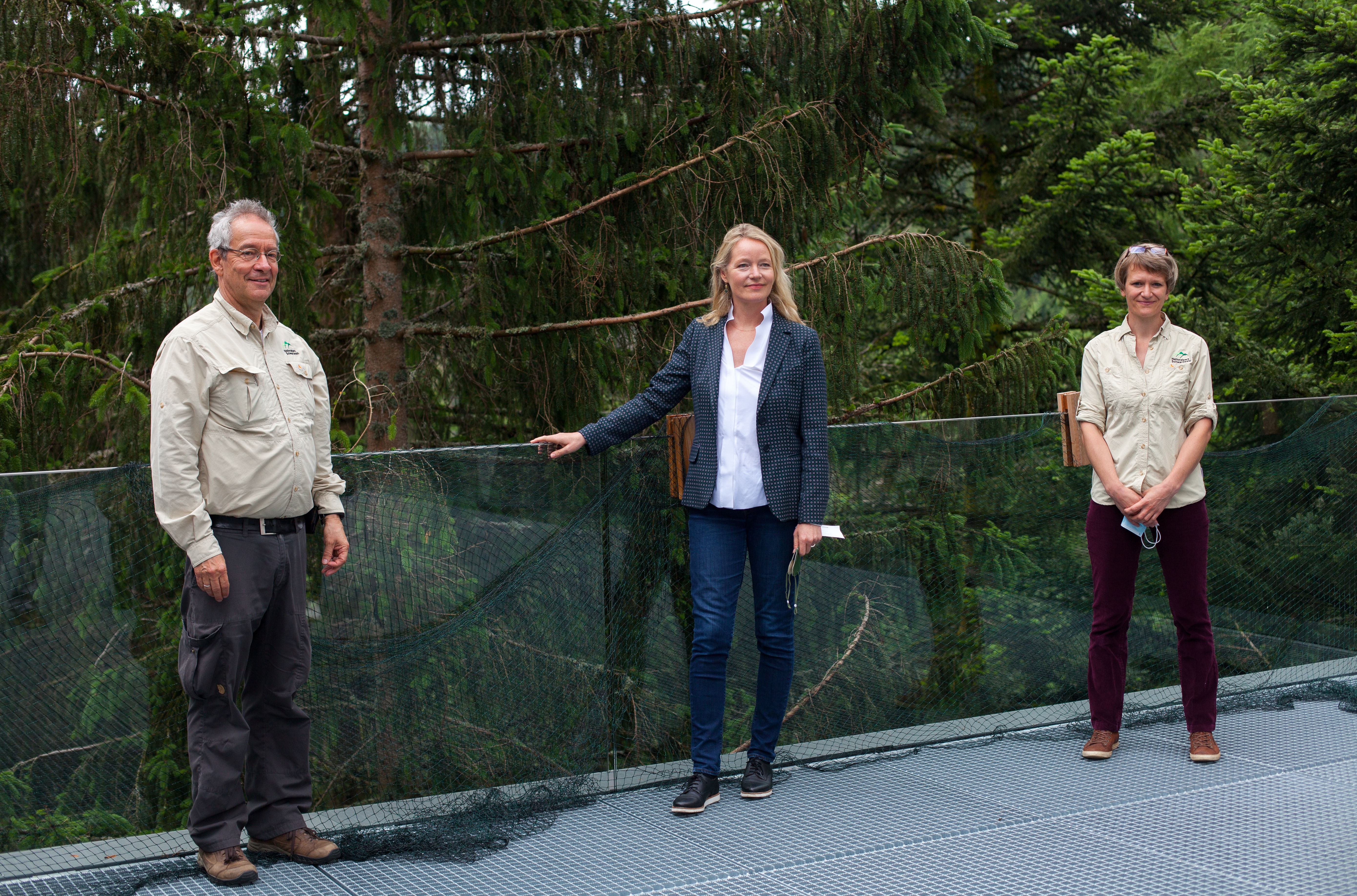 Ein Mann und zwei Frauen stehen vor einer Kulisse mit Baumwipfeln. Foto: Bartek Langer