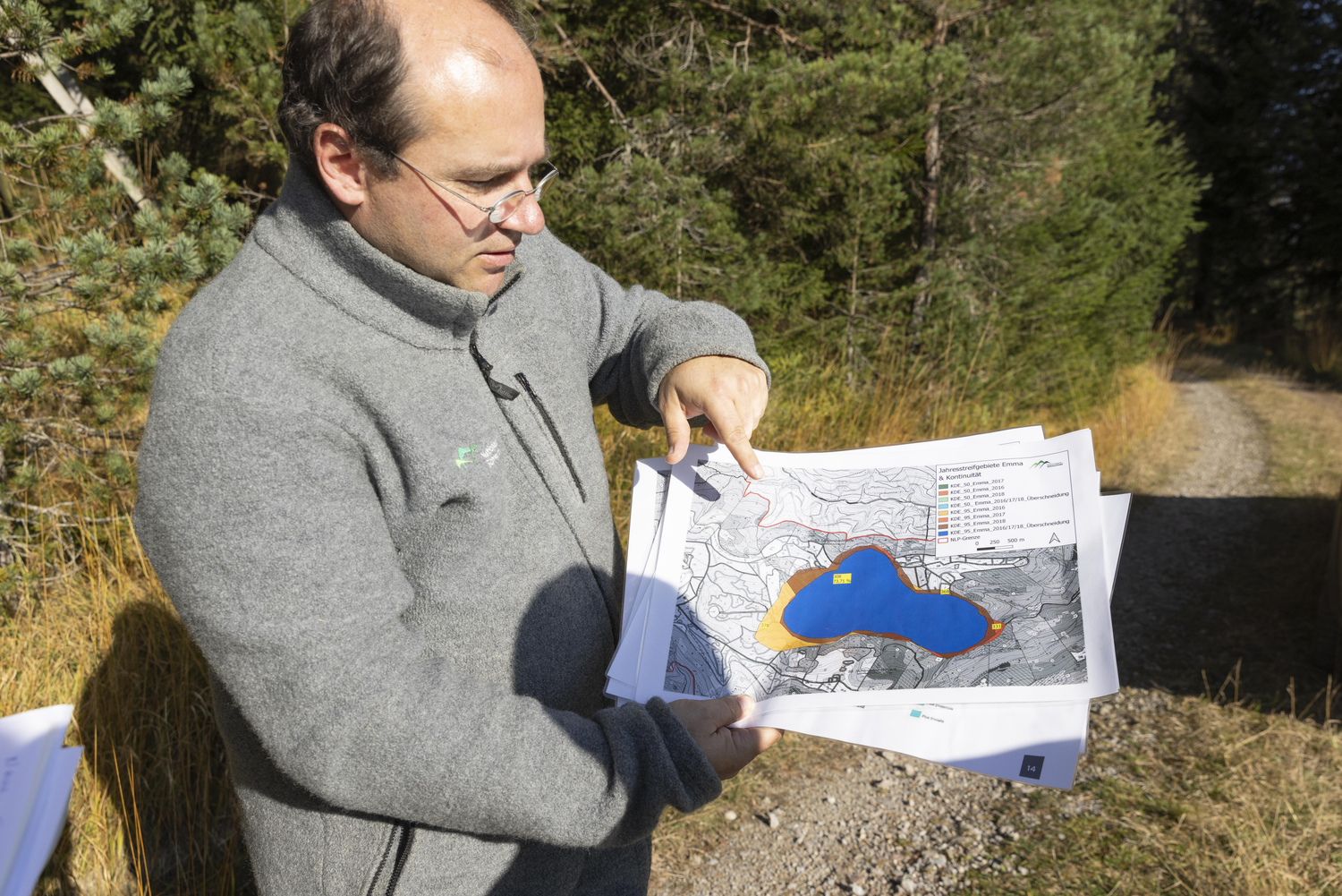 Ein Mann in grauer Jacke steht auf einen Wanderweg und hält mehrere Blätter in der Hand Foto: Ulrike Klumpp