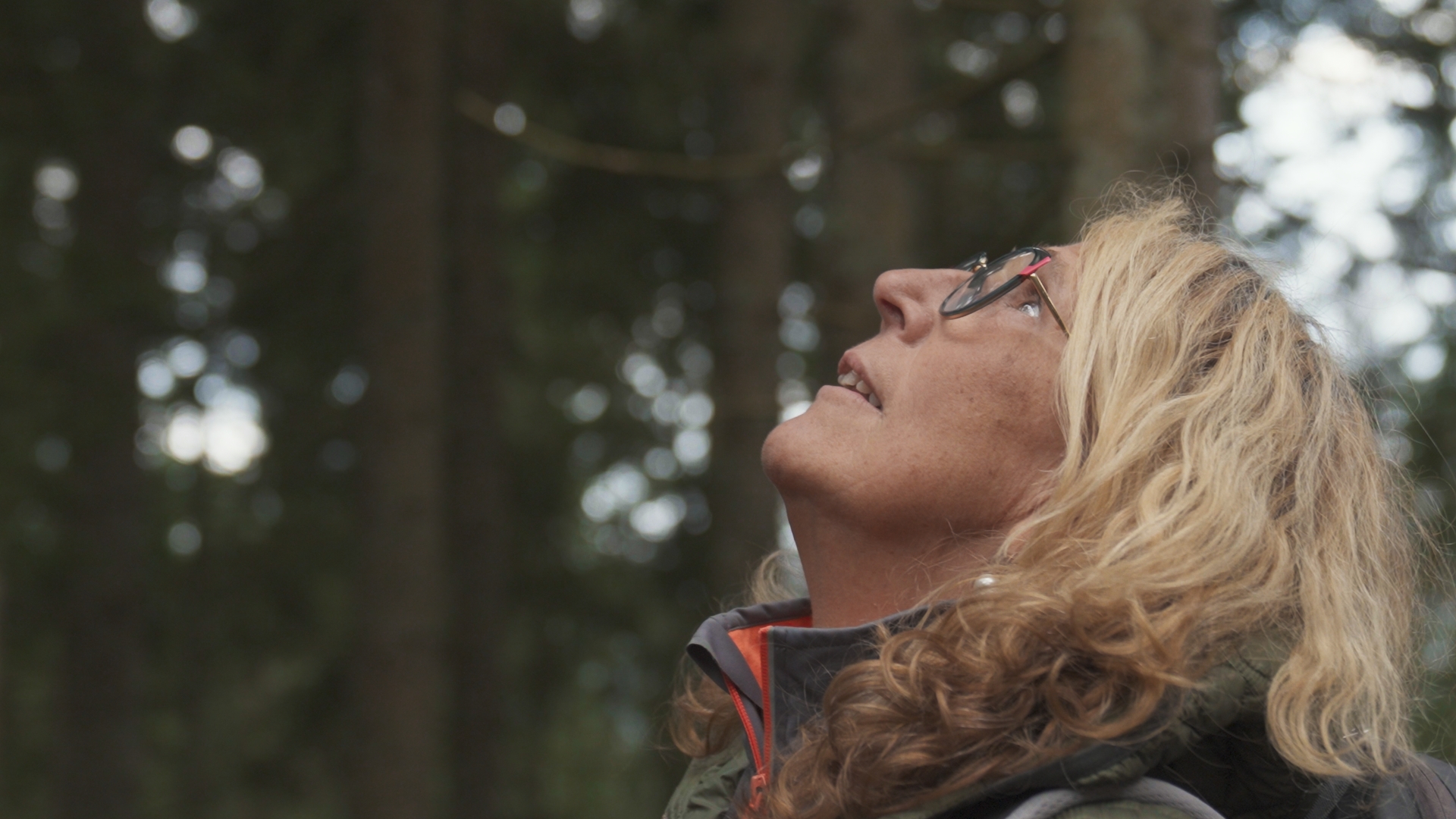 Eine Frau mit blonden, lockigen Haaren und Brille blickt im Profil staunend nach oben. Foto: Juliane Schrempp 