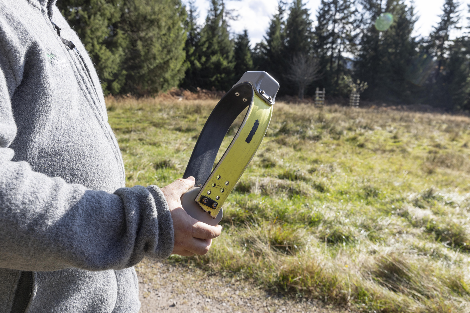 Ein Mann Mann in grauer Jacke ist angeschnitten, man sieht nur seine Hand, die einen gelben Ring mit einem kleinen gruaben Kasten oben drauf hält. Foto: Ulrike Klumpp